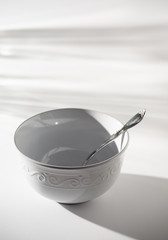 Empty White Cereal or Soup Bowl with a Silver Spoon on a White Background