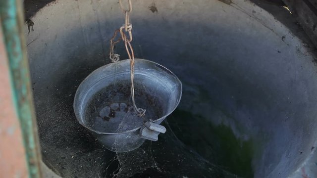 Old abandoned well. A leaky web-covered bucket hangs in a well.