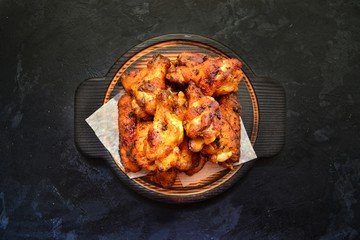 Fried chicken wings. Chicken wings on a dark background on a blackboard. Barbecue meat, grill. Sauce in bowls, ketchup, mayonnaise, mustard, cheese sauce. Appetizing fried meat. Place for your text