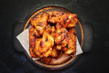 Fried chicken wings. Chicken wings on a dark background on a blackboard. Barbecue meat, grill. Sauce in bowls, ketchup, mayonnaise, mustard, cheese sauce. Appetizing fried meat. Place for your text