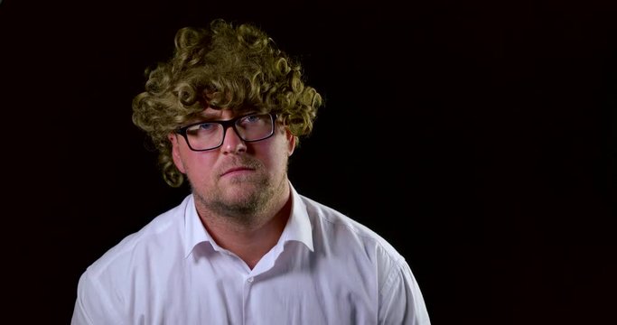 sad guy looks and takes off glasses and curly hair wig