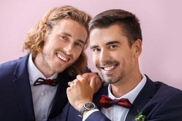 Portrait of happy gay couple on their wedding day against color background