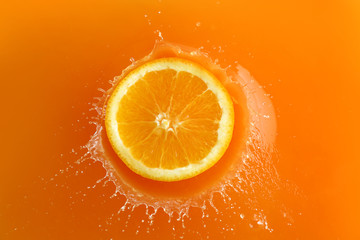 Falling of orange piece into juice, top view