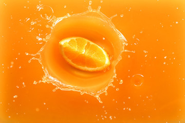 Falling of orange piece into juice, top view