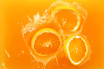 Falling of orange slices into juice, top view