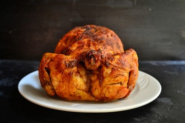 Baked whole chicken. Appetizing whole chicken with a crispy golden crust on a dark concrete table background. Festive, Christmas dish.
