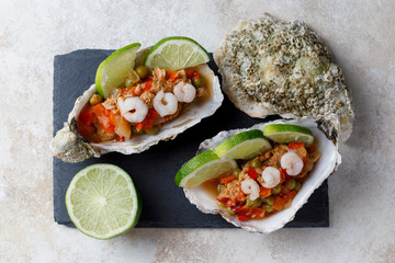 Oyster shell with seafood salad and lime on dark background