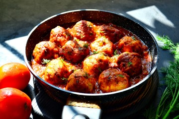 Meatballs in tomato sauce. Chicken meatballs. Meatballs in a pan on a dark table background isolated.
