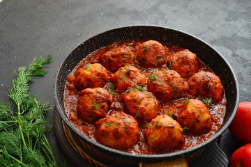 Meatballs in tomato sauce. Chicken meatballs. Meatballs in a pan on a dark table background isolated.