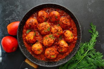 Meatballs in tomato sauce. Chicken meatballs. Meatballs in a pan on a dark table background isolated.