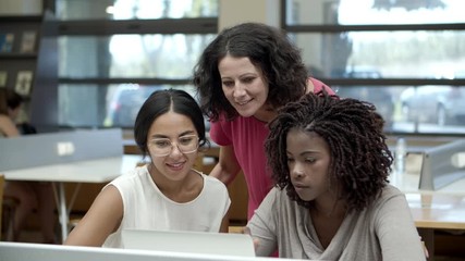 Front view of mature students discussing new project. Cheerful women talking while looking at laptop. Education concept - Powered by Adobe