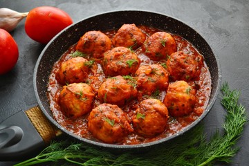 Meatballs in tomato sauce. Chicken meatballs. Meatballs in a pan on a dark table background isolated.