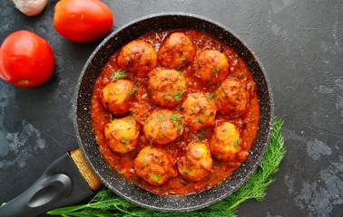 Meatballs in tomato sauce. Chicken meatballs. Meatballs in a pan on a dark table background isolated.