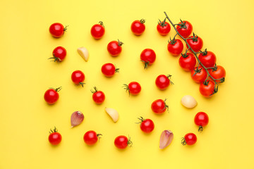 Many fresh tomatoes with garlic on color background