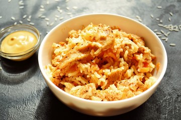 Rice in a white bowl. Rice dish on a dark table background. Pilaf, rice porridge, cooked rice with vegetables. Healthy vegetarian food.