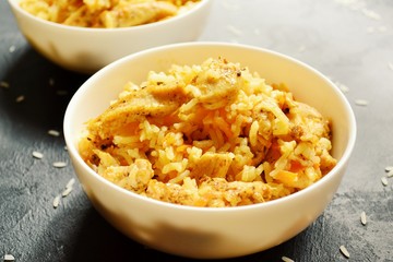 Rice in a white bowl. Rice dish on a dark table background. Pilaf, rice porridge, cooked rice with vegetables. Healthy vegetarian food.