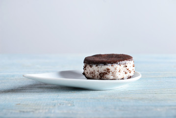 Plate with tasty ice cream cookie sandwich on wooden table
