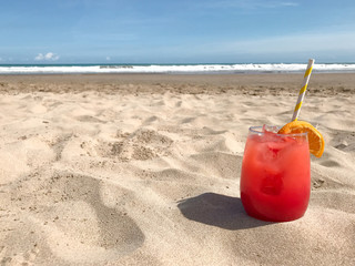 glass with red tasty cocktail stands on the beach against the sea 1