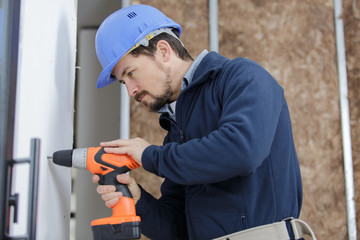 construction worker using drill to install door