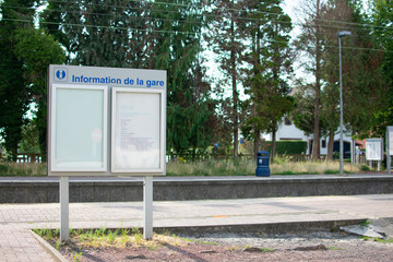 Waterloo,Belgium - July 25 2019: Information panel at the Waterloo train station on a sunny day with a blue garbage can in the background