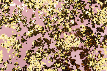 Golden confetti glitter on pink background. Festive holiday pastel backdrop. Greeteng cards template.