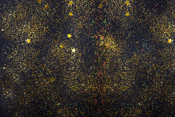 Gold glitter holiday texture on a black background. Golden explosion of confetti. Golden grainy abstract texture on a black background. Night sky style background.