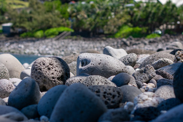 Close-up of volcanic rock pebble beach on sunny day