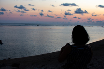 Female silhouette on beach against marshmallow orange pink sunset