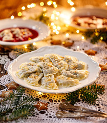 Christmas dumplings stuffed with mushroom and cabbage on a white plate on a holiday table....