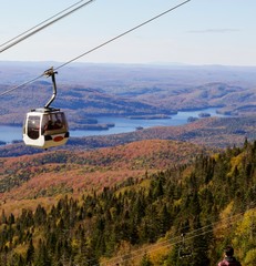 Gondola rising above the trees turning yellow and red in fall