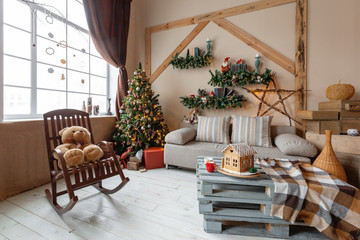 Christmas morning in the bright living room. Homemade gingerbread house on background room decorated for Christmas.