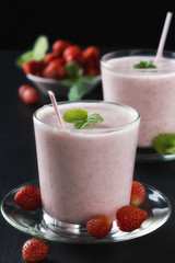  Strawberry smoothie or milkshake in glass cup on black rustic background, healthy food for breakfast and snack
