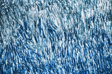 Bottom view with a shallow depth of field of lots of hanging blue and teal ribbons on the street on a bright day, they overlap each other, sway in the wind, and forming turbulent patterns