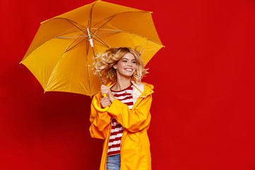 young happy emotional cheerful girl laughing and jumping with yellow umbrella   on colored red background.