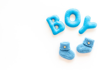 Children's birthday concept. Word boy near booties on white background top view frame copy space