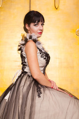 alluring sexy woman in evening dress posing over golden studio background