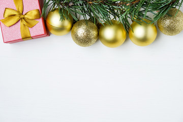 Fototapeta na wymiar Golden Cristmas balls, pine branches, gift on top of background with copy space.