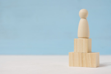Abstract wooden figure of man on toy blocks are located as podium.