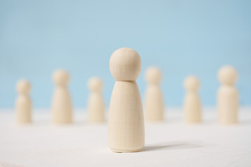 Wooden figures of man in the center and people stand apart from each other.
