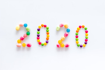 Sweet New Year design. 2020 laid out with candy on white background top view copy space