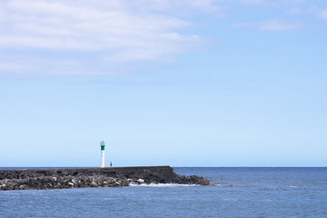 Lonely person standingnext to lighthouse at Saint Pierre harbor Réunion island