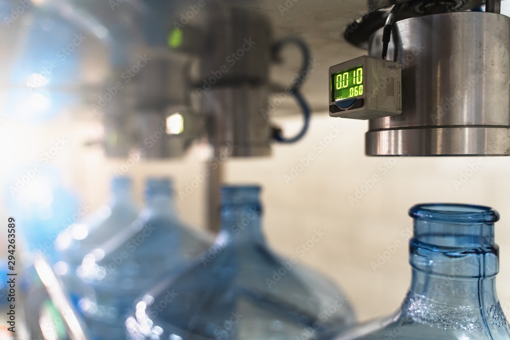 Wall mural Plastic bottles on conveyor for checking integrity of containers under pressure at factory for production of purified drinking water