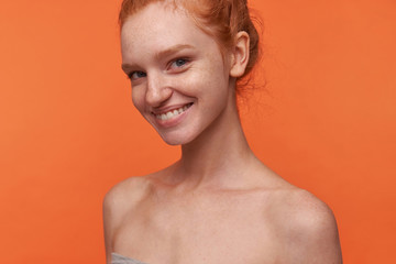 Indoor photo of lovely young lady white perfect teeth wearing her foxy hair in knot standing over...