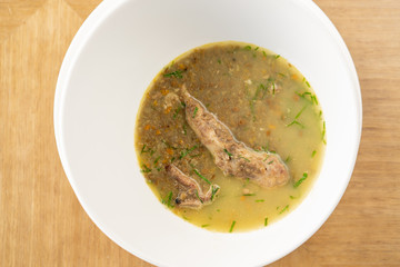 A bowl of homemade chili lentil soup with meat on wooden table. Restaurant menu