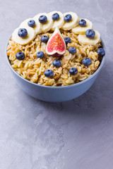 Healthy breakfast. Oatmeal with blueberries, banana and figs. Oatmeal with fruits and berries in a bowl. Cooked oatmeal on cement background. Copy space