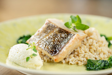 Roasted pike perch or cod fish with bulgur. Dish decorated with a spinach. Restaurant menu
