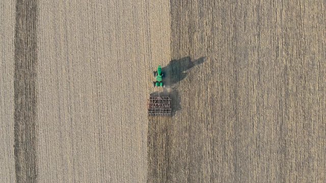 Drone Footage Above a Green Tractor Plowing a Farmers Field on a summer day in Canada 4K.