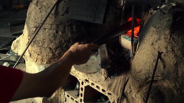 Glass Furnace. This stock video features a worker placing broken pieces of glass inside a furnace to repurposes the materials.