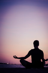 Silhouette of man doing yoga on the beach