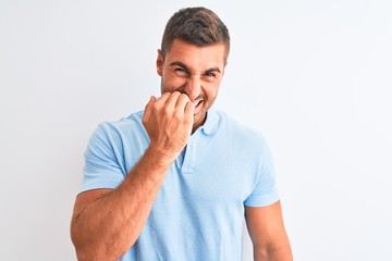 Young handsome elegant man wearing blue t-shirt over isolated background looking stressed and nervous with hands on mouth biting nails. Anxiety problem.